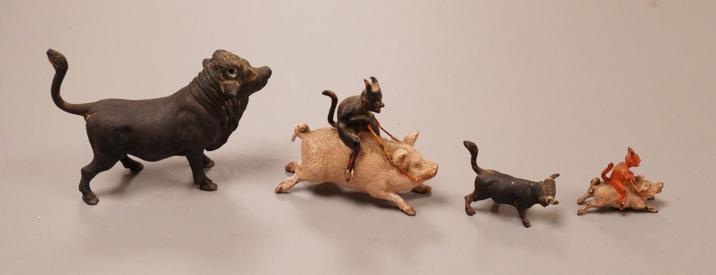 Four Austrian cold painted bronze miniature groups or figures, two of the devil riding a pig and two of cattle, tallest 4cm